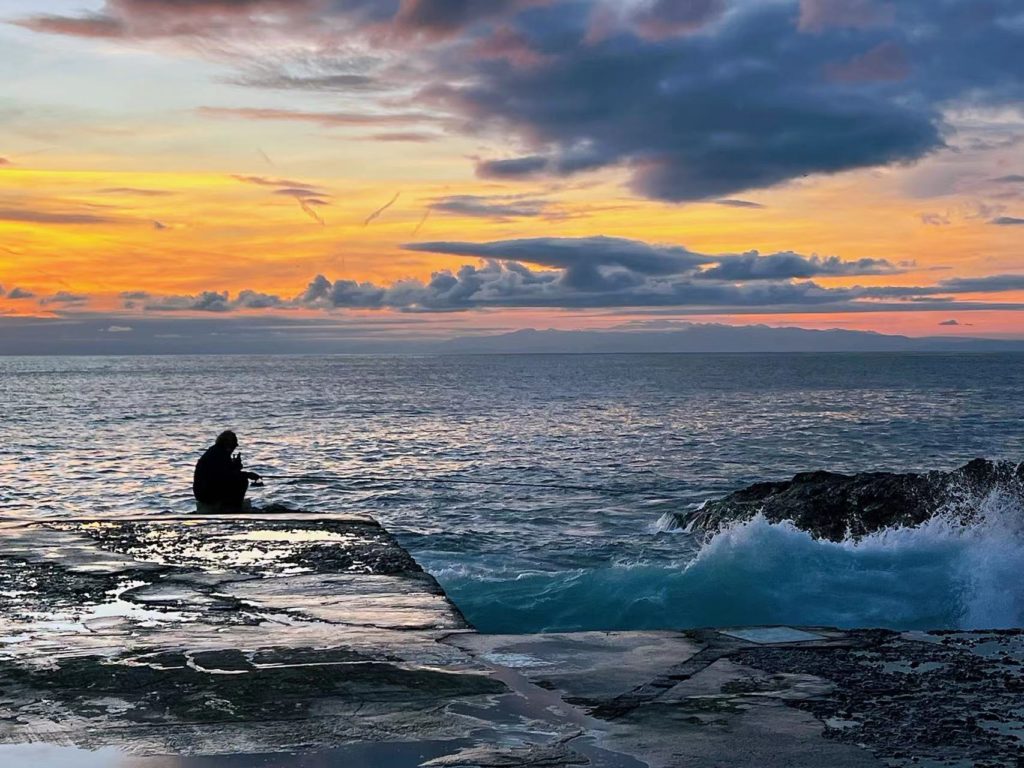 Angler an der ligurischen Küste vor Sonnenuntergang